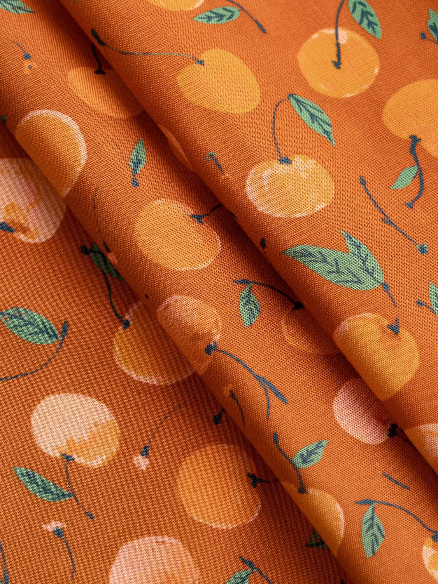 F-DEA237-Cherry-Print-Modal-Challis-Deadstock-Terracotta-Apricot-and-Basil-Core-Fabrics-fold.webp