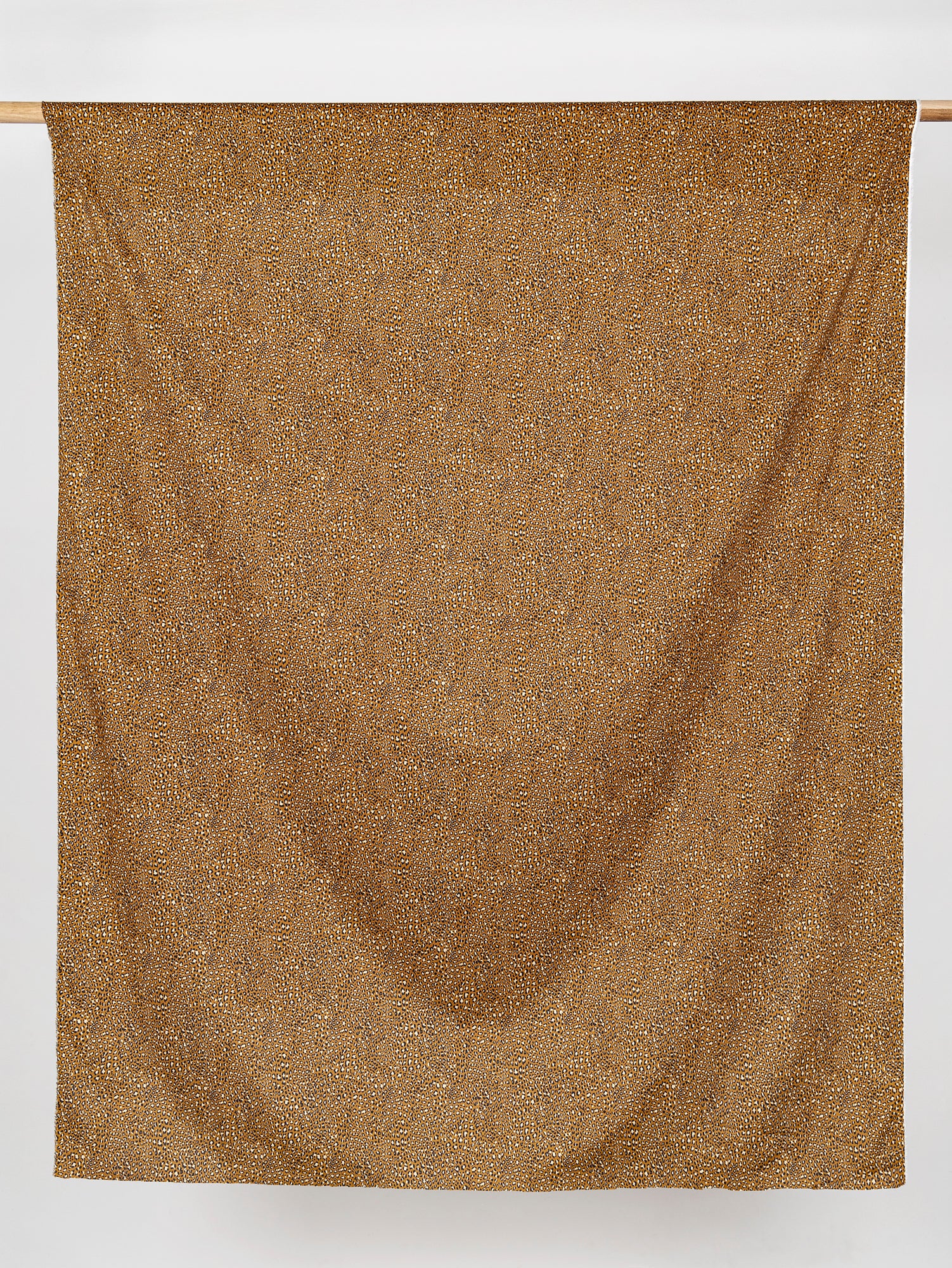 F-COT328-Ditzy-Leopard-Print-Cotton-Lawn-Ochre-Black-Beige-Core-Fabrics-draped