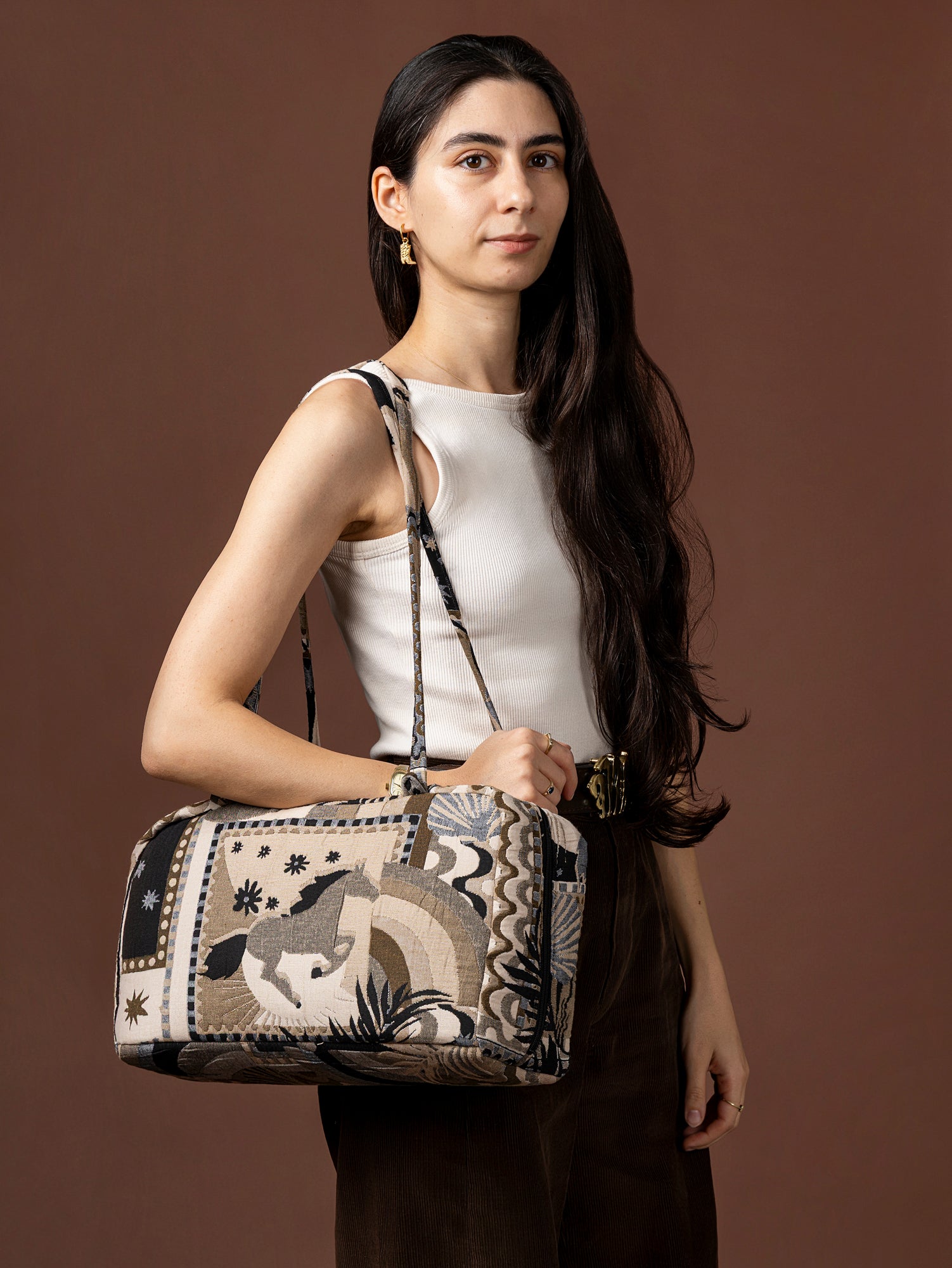 Woman holding a patterned handbag against a brown background