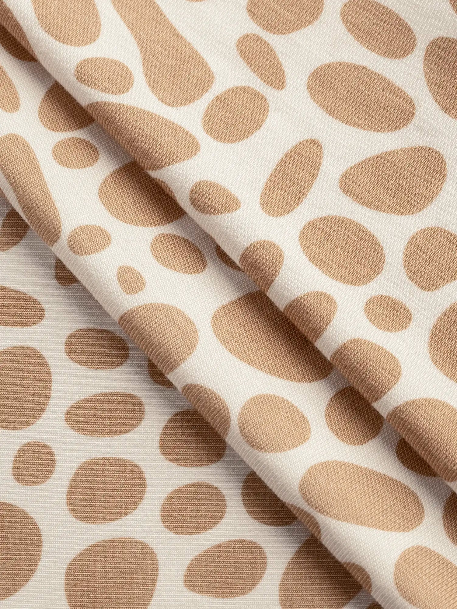 F-DEA235-Pebble-Print-Bamboo-Spandex-Knit-Deadstock-Ivory-and-Sand-Core-Fabrics-fold.webp