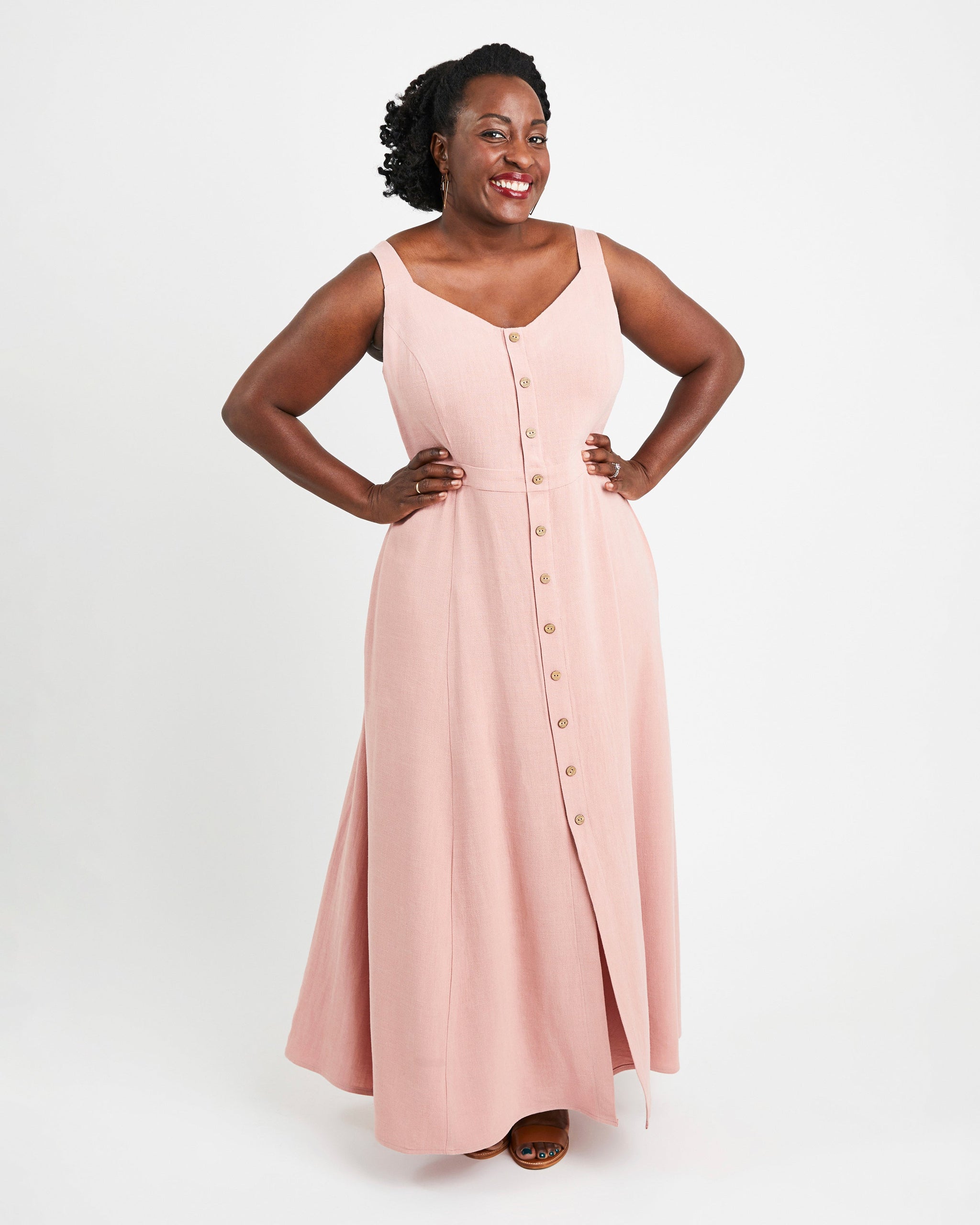 Woman wearing a pink sleeveless dress with buttons on a white background. This is the Holyoke Maxi Dress & Skirt sewing pattern from Cashmerette.